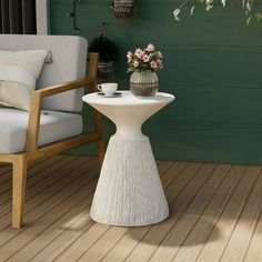 a white table sitting on top of a wooden floor next to a chair and potted plant