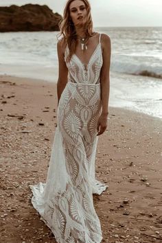 a woman standing on top of a beach next to the ocean wearing a white dress