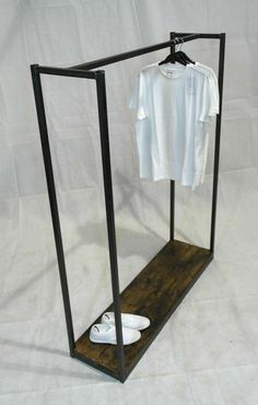 a white shirt is hanging in a black frame with shoes on the floor and a pair of slippers underneath it