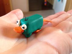 a hand holding a green toy with googly eyes