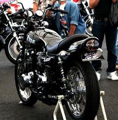 several motorcycles are parked in a row on the street with people looking at them and taking pictures