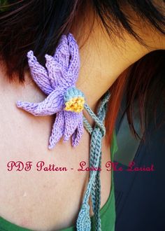 a close up of a woman's neck wearing a knitted necklace with flowers on it