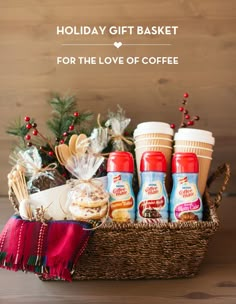 a basket filled with coffee and snacks on top of a wooden table next to a christmas tree