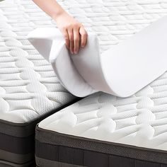 the mattress is being unwrapped and placed on top of each other with one person's hand