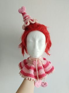 a doll with red hair wearing a pink and white striped dress on it's head