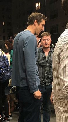 two men are talking to each other in front of a group of people standing around