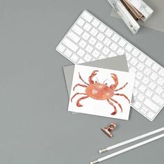 a computer keyboard sitting on top of a desk next to an orange crab sticker