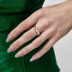 a woman's hand wearing a ring with a diamond on it and a green dress