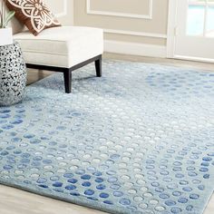 a blue rug with circles on it in front of a white chair and window sill