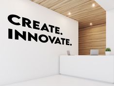 a white reception table with a laptop on it in front of a wall that says create innovate