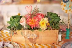 a wooden box filled with flowers on top of a table next to plates and utensils