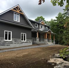 a large gray house sitting on top of a dirt field