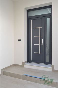 an empty room with a black door and some steps leading up to the front door