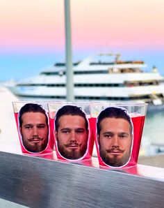 three men with beards are sitting in front of a cruise ship on the water