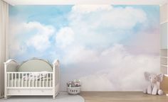 a baby's room with clouds painted on the wall and a crib next to it