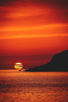 the sun is setting over an island in the ocean