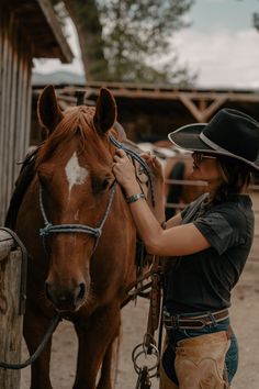 a woman wearing a cowboy hat standing next to a brown horse