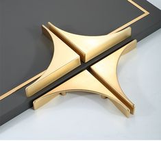 an image of a gold and black object that is on top of a table in the shape of a cross