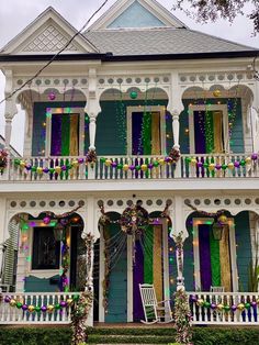 a white house with purple and green decorations on it's balconies is decorated for mardi gras