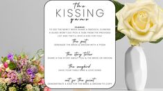 a white vase with flowers in it next to a sign that says the kissing poem