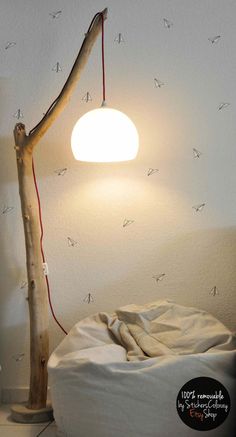 a lamp that is sitting on top of a bed next to a tree branch with birds drawn on it