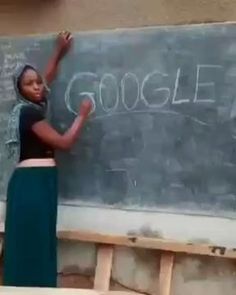 a woman standing in front of a blackboard with google written on it and writing on the chalk