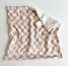 a pink and white checkered blanket laying on top of a table