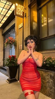 a woman in a red dress is posing for the camera with her hands on her face