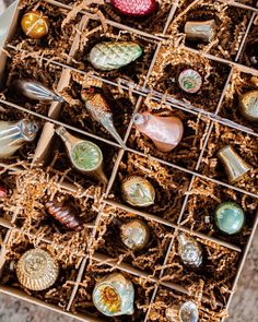 a box filled with lots of different types of glass ornaments on top of a table