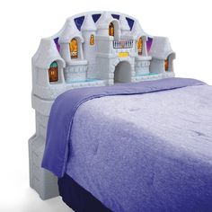 a bed with a castle headboard and purple bedspread in front of it