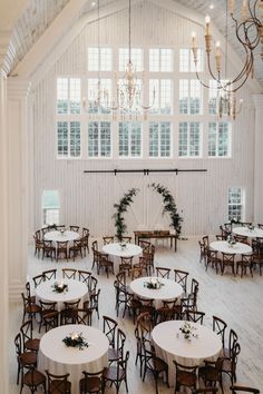 a room filled with tables and chairs covered in white tablecloths under a chandelier