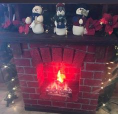 a fire place with christmas decorations and stuffed animals sitting on top of it, in front of a brick fireplace