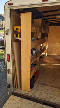 the inside of a horse trailer with its doors open and shelves full of items in it