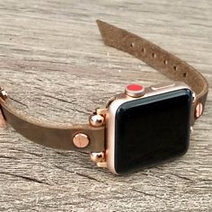 an apple watch sitting on top of a wooden table next to a brown leather band