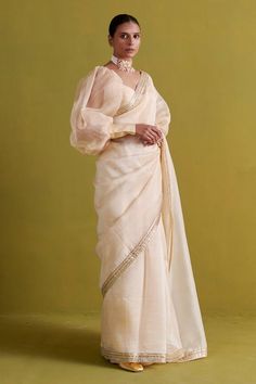 Beige saree in organza base hand embroidered with plumeria swirl border embroidery using gota patti and thread work. Paired with a bishop sleeves sweetheart neck raw silk blouse and shantoon petticoat. - Aza Fashions Elegant Fitted Pre-draped Saree With Gota Work, Luxury Semi-stitched Pre-draped Saree With Gota Work, Festive Pre-draped Organza Saree With Gota Work, Elegant Art Silk Blouse Piece With Gota Work, Anarkali Organza Blouse For Diwali, Party Organza Pre-draped Saree With Gota Work, Designer Organza Blouse With Traditional Drape, Elegant Gota Work Blouse Piece For Navratri, Wedding Blouse Piece With Gota Work On Organza