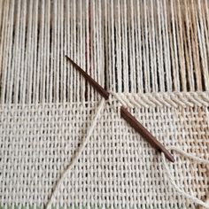 two pairs of scissors are on top of a piece of woven material that has been stitched together