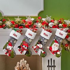 christmas stockings hanging from a mantel decorated with red, white and green decorations