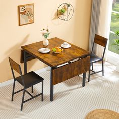 a dining room table with two chairs and a bowl of fruit on the table next to it