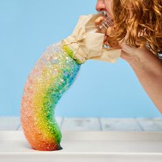 a woman with curly hair is eating something out of a plastic bag that has been covered in rainbow sprinkles