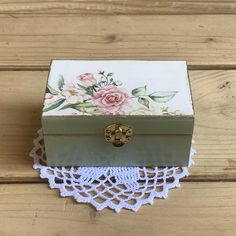 a small wooden box sitting on top of a table next to a lace doily