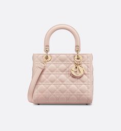 The Lady Dior bag epitomizes the House's vision of elegance and beauty. Sleek and refined, the style is timeless. It is crafted in powder pink lambskin with Cannage stitching, creating the instantly recognizable quilted texture. Pale gold-finish metal D.I.O.R. charms lend elegant appeal. Featuring a thin, removable leather shoulder strap, the medium Lady Dior bag may be carried by hand or worn crossbody.. Sac Lady Dior Medium, Lady D Joy Bag, Galaxy Stuff, Lady D, Lady Dior Handbag, Dior Book Tote, Small Lady, Dior Handbags, Wallet Pouch