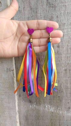 a pair of colorful tasseled earrings in the palm of someone's hand