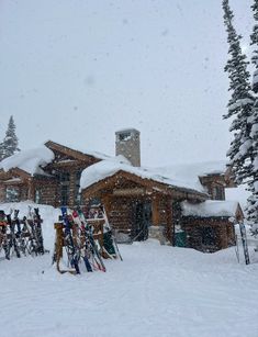 a ski lodge covered in snow with lots of skis on the ground and trees