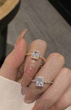 a woman's hand with two rings on her fingers and an engagement ring in the middle