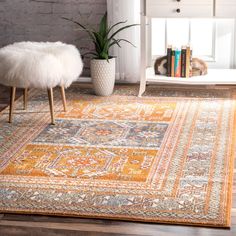 a large rug with an orange and yellow design on the floor next to a white table