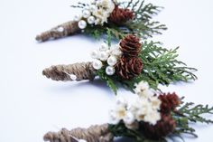 three pine cones are adorned with white and brown flowers, pearls and twine needles