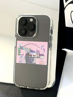 an iphone case with a sticker on it sitting next to a computer keyboard and monitor