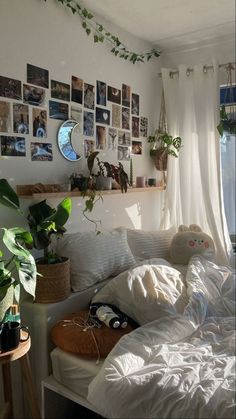 an unmade bed with plants and pictures on the wall