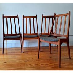 three wooden chairs sitting next to each other on top of a hard wood floored floor