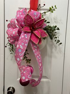 a pink and white bow hanging on a door